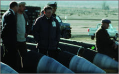 Men standing in desert next to disarmed cruise missiles.